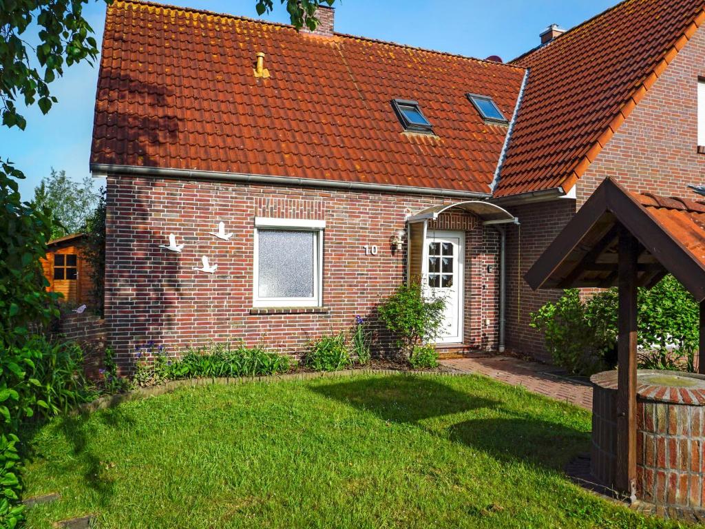 une maison en briques avec un toit rouge et une cour dans l'établissement Holiday Home Entenkoje by Interhome, à Dornum