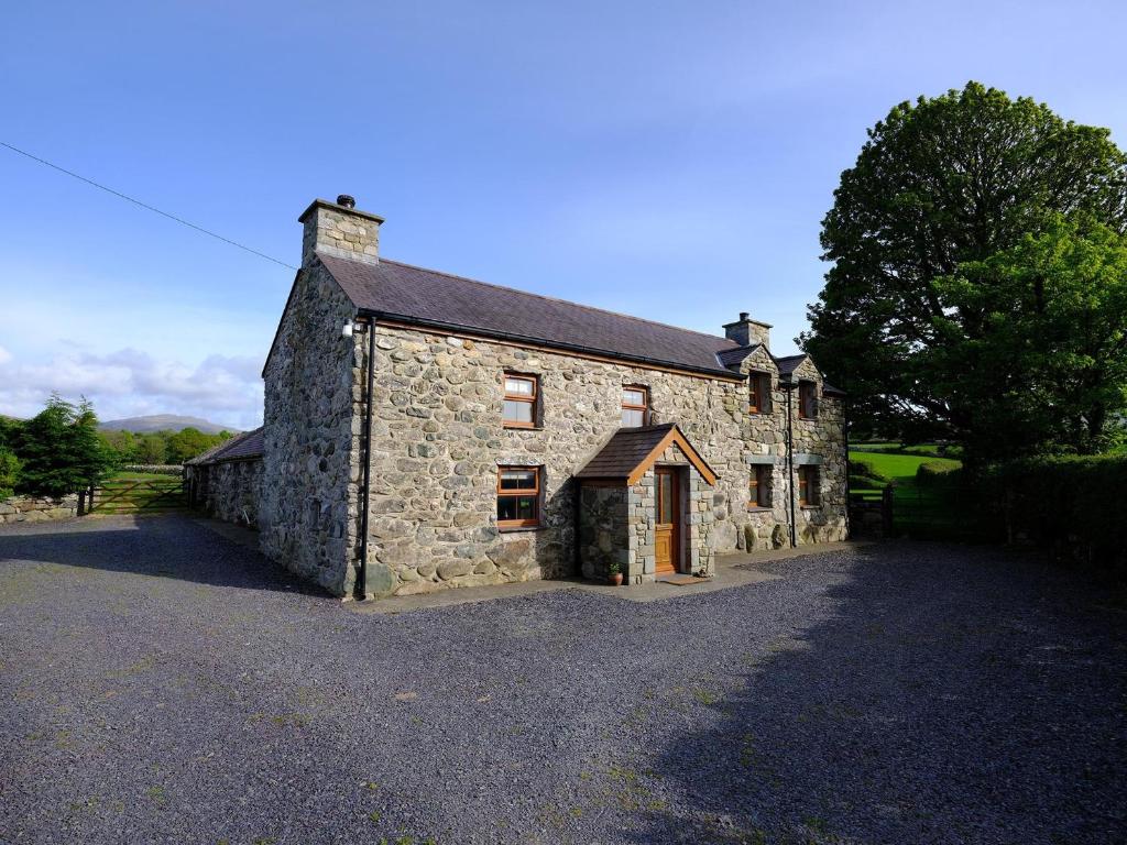 an old stone house sitting on the side of a road at Pen Y Bont in Llandwrog