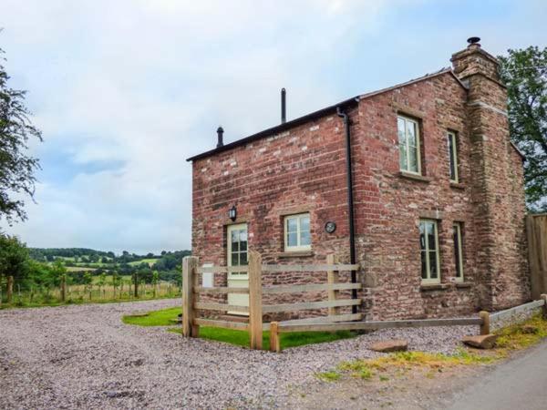 a brick building with a fence in front of it at Rose Cottage in Monmouth