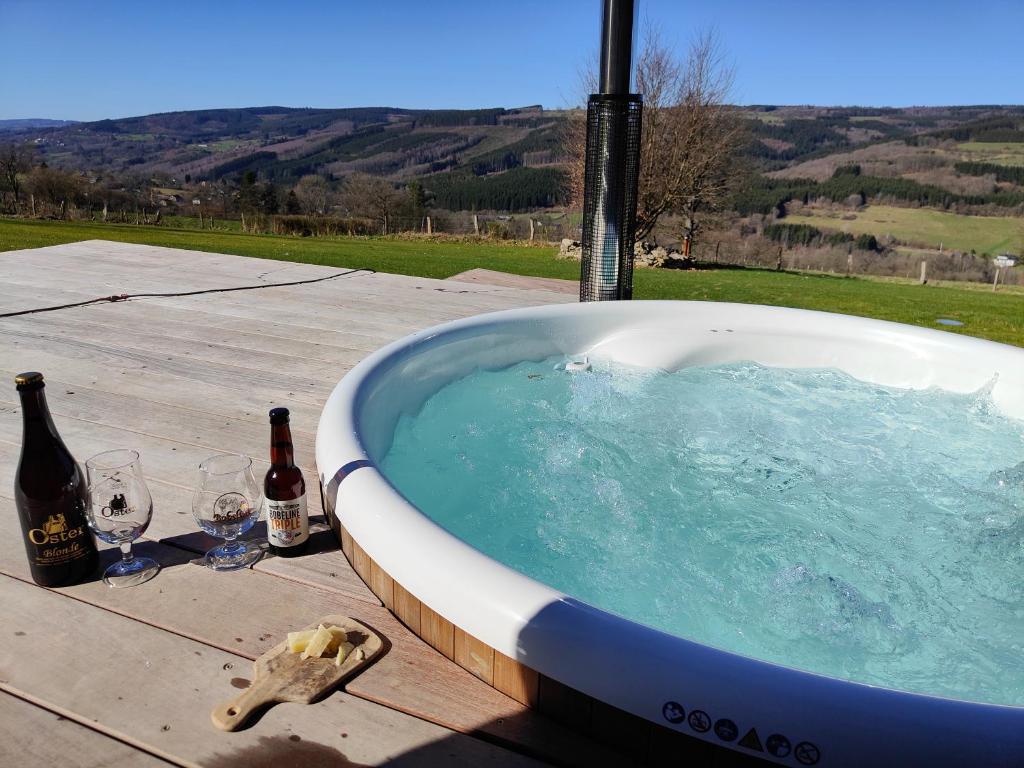 a bath tub with two bottles and two wine glasses at Le Clos des Brumes in Stoumont