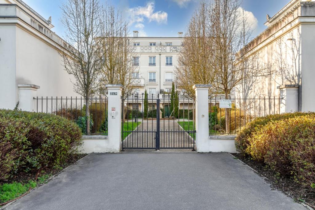 a gate in front of a white building at Cocoon 2 Proche - Disney Paris- Parking gratuit in Serris