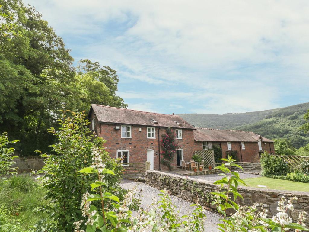 an exterior view of a brick house with a garden at Bryn Howell Stables in Trevor