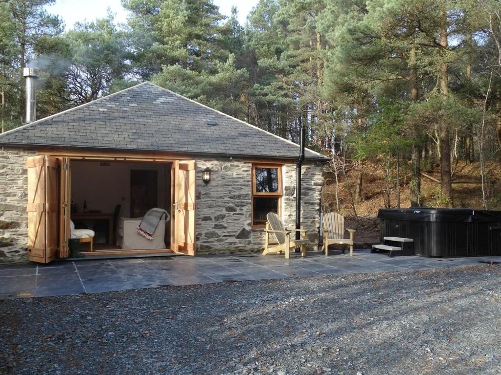 a small stone house with chairs and a trash can at Rock View Cottage in Gunnislake