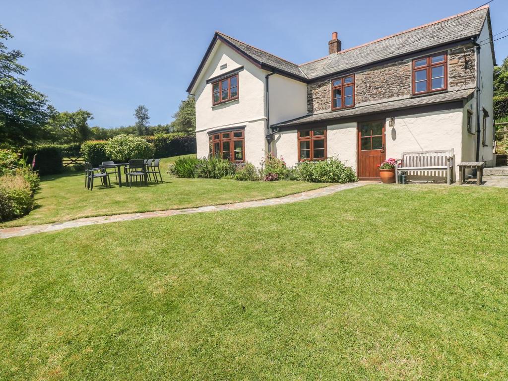 a house with a grassy yard with two benches at Meadow Lea in Liskeard