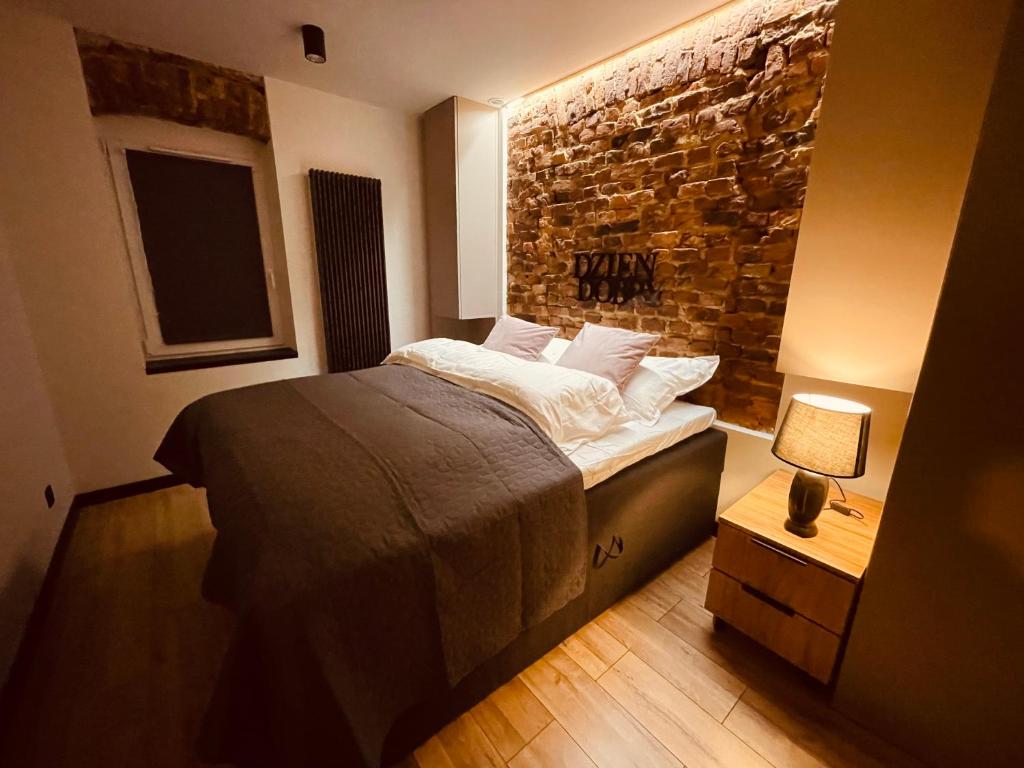 a bedroom with a bed and a brick wall at Apartamenty KTW Park Śląski - Family DELUX in Katowice