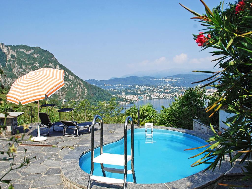 a swimming pool with chairs and an umbrella at Holiday Home Casa Ursula by Interhome in Pugerna