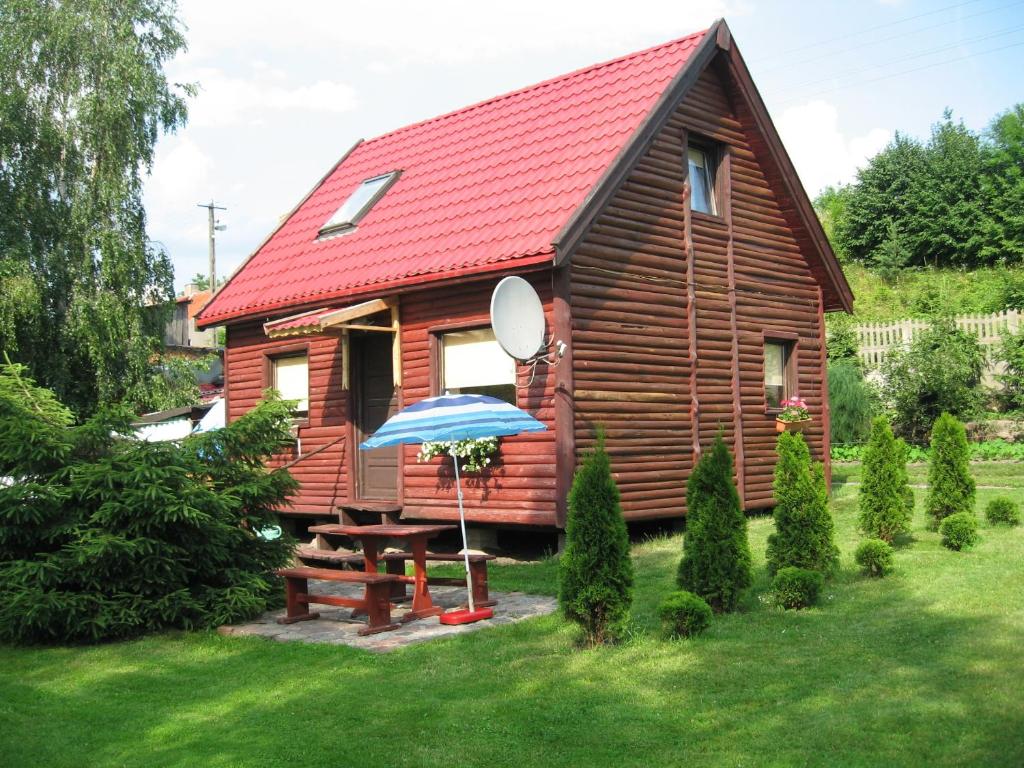 a wooden cabin with a picnic table and an umbrella at Dom nad Jeziorem in Rasząg