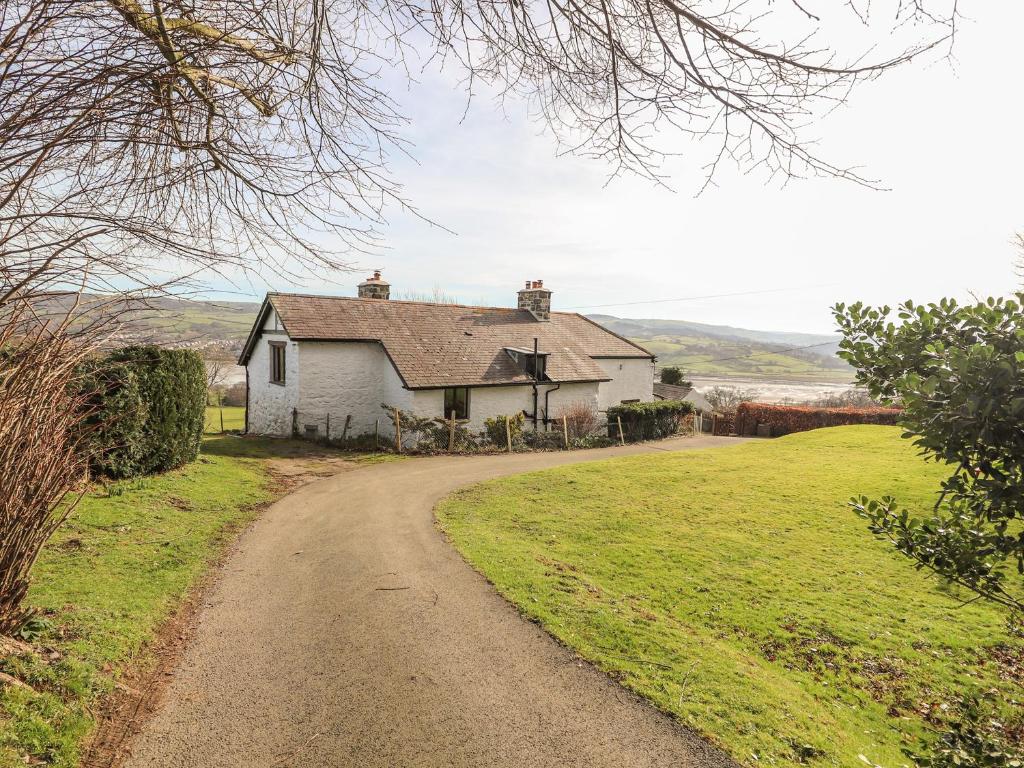 a small white house on a dirt road at Cymryd Uchaf in Conwy