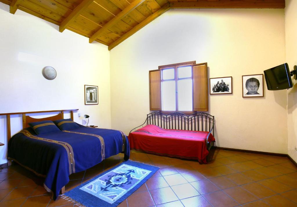 a bedroom with two beds and a tv and a rug at Chez Daniel in Antigua Guatemala