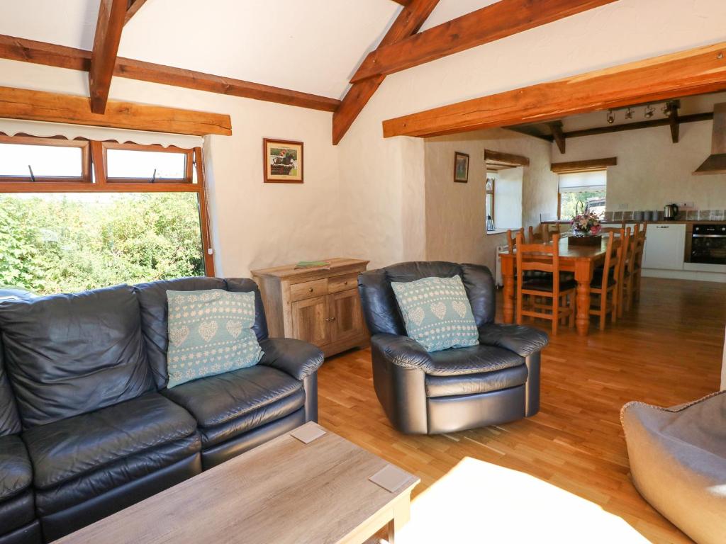 a living room with two leather chairs and a table at Stable Cottage in Clynderwen