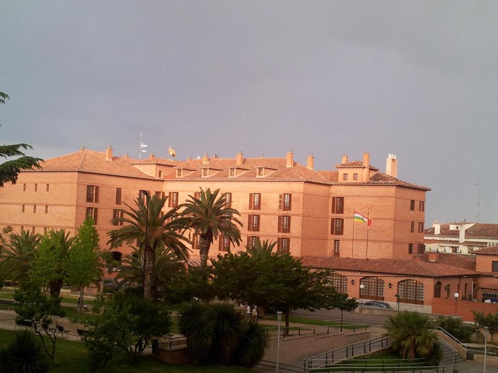 een groot bakstenen gebouw met palmbomen ervoor bij Parador de Calahorra in Calahorra