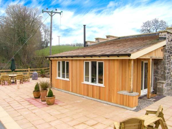 a small wooden building with a patio and a table at The Lambing Shed in Newmarket