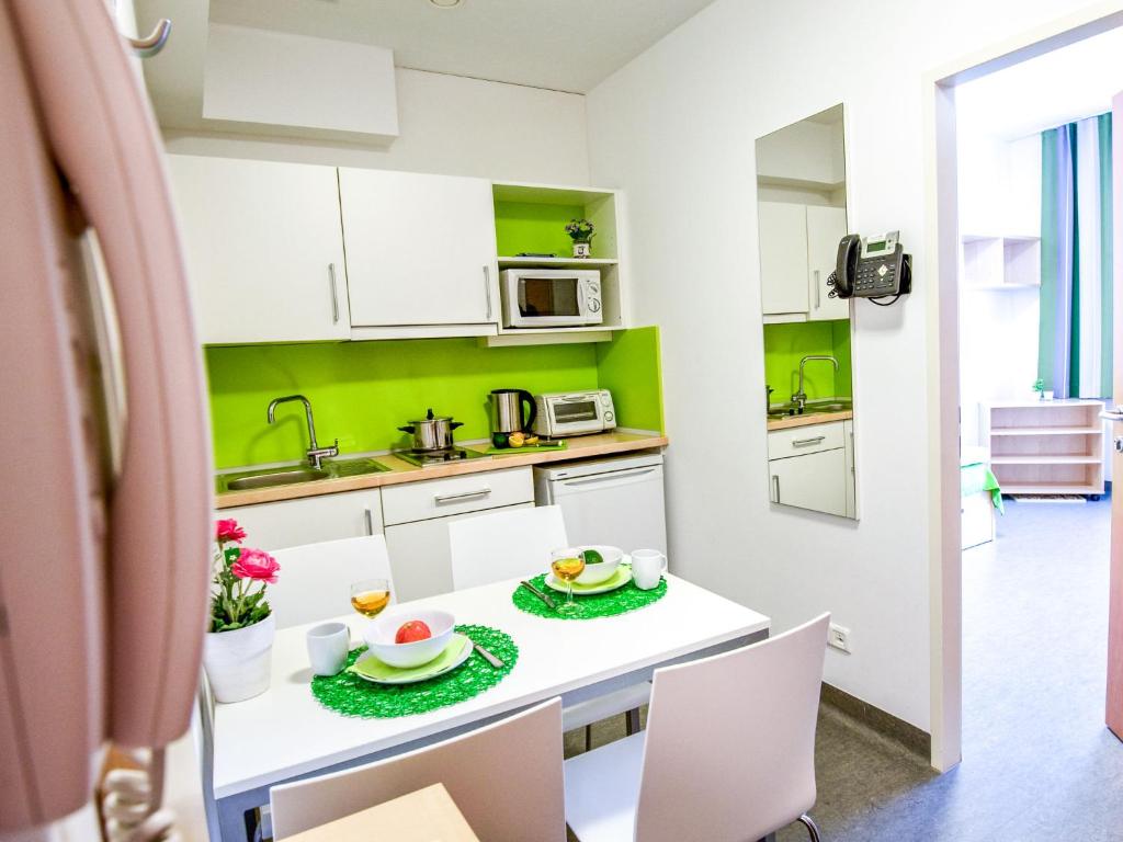 a kitchen with white cabinets and a white table and chairs at Apartment smart living by Interhome in Sankt Ulrich