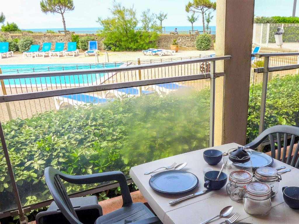 a table with plates and silverware on a balcony with a view of the ocean at Apartment Mer et Golf by Interhome in Chambre-dʼAmour