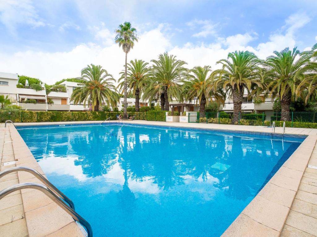 a large blue swimming pool with palm trees in the background at Studio Les Cyprianes-6 by Interhome in La Grande Motte