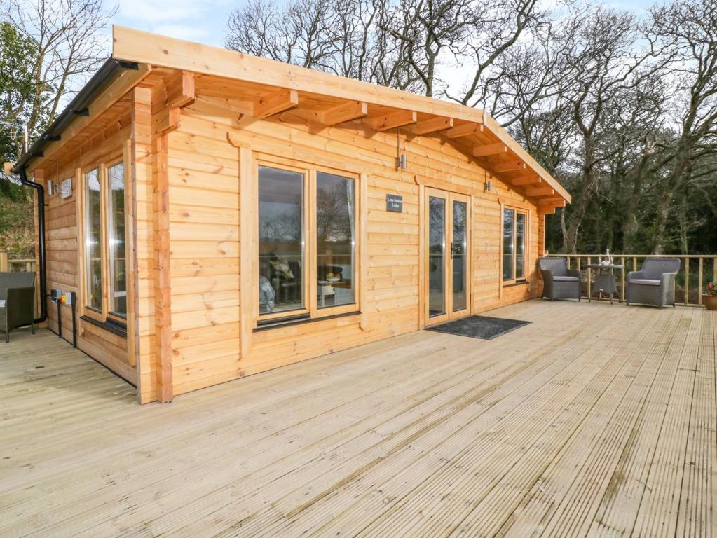 a small wooden cabin with a large deck at Little Orchard Lodge in Truro