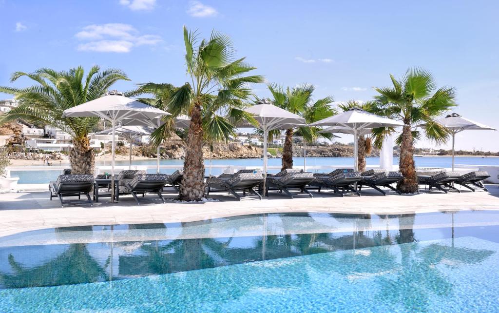 einen Pool mit Palmen, Stühlen und Sonnenschirmen in der Unterkunft Petinos Beach Hotel in Platis Gialos