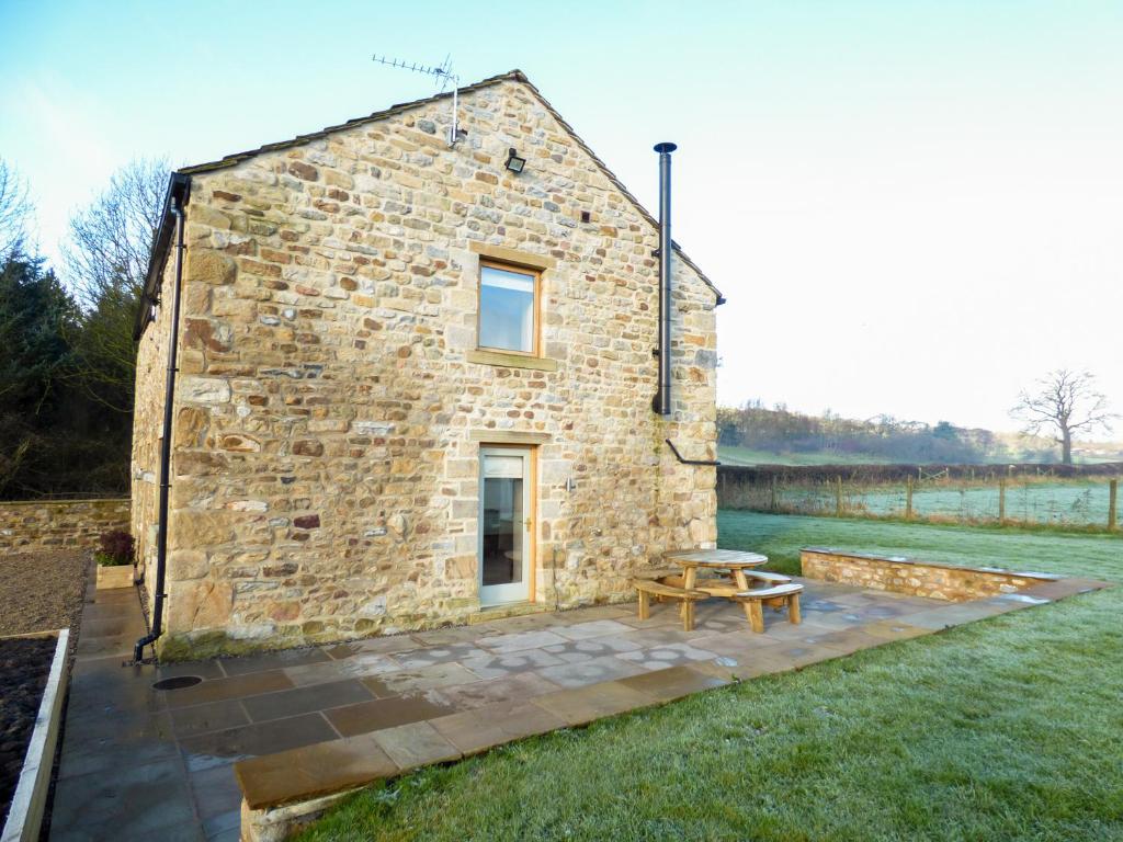 a stone house with a picnic table in front of it at Cow Hill Laith Barn in Sawley