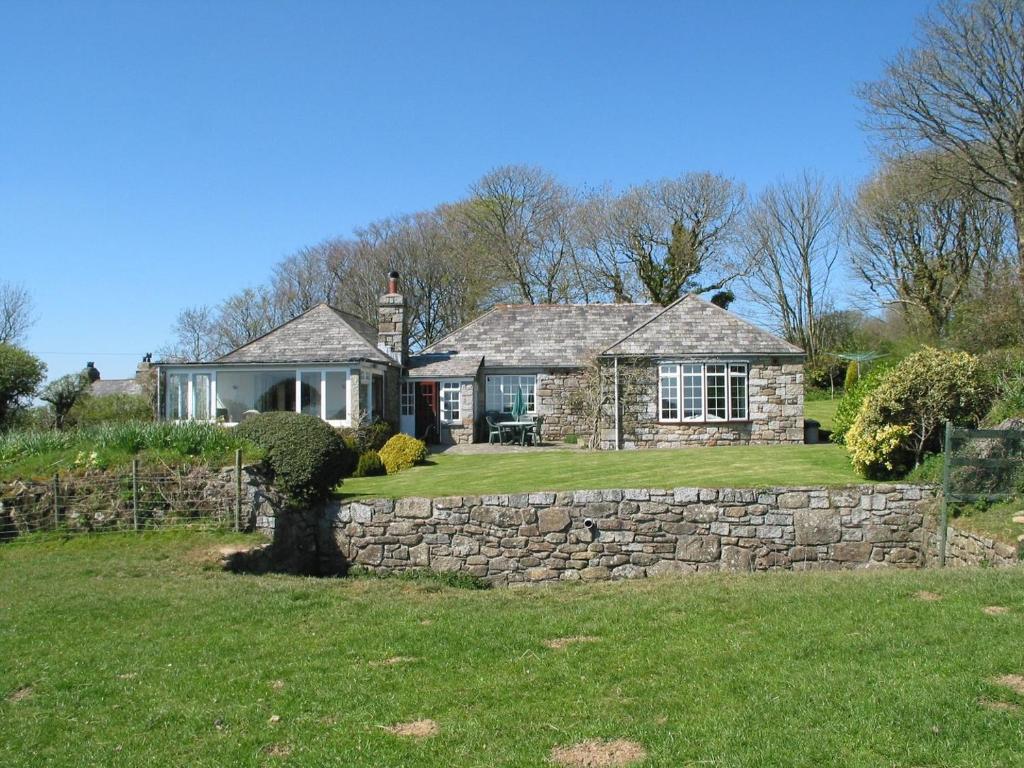 a house with a stone wall and a yard at Higher Tumrose in Blisland