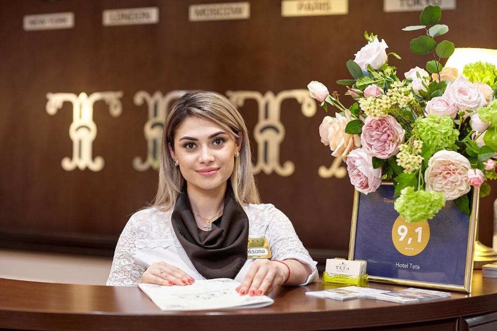una mujer sentada en una mesa con flores en Hotel Teta, en Timashevsk