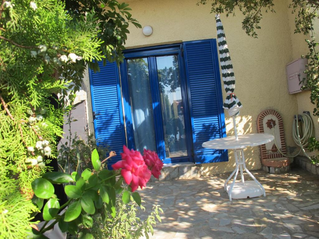 a patio with blue doors and a table and flowers at Porto Kastri Studios in Kastrí
