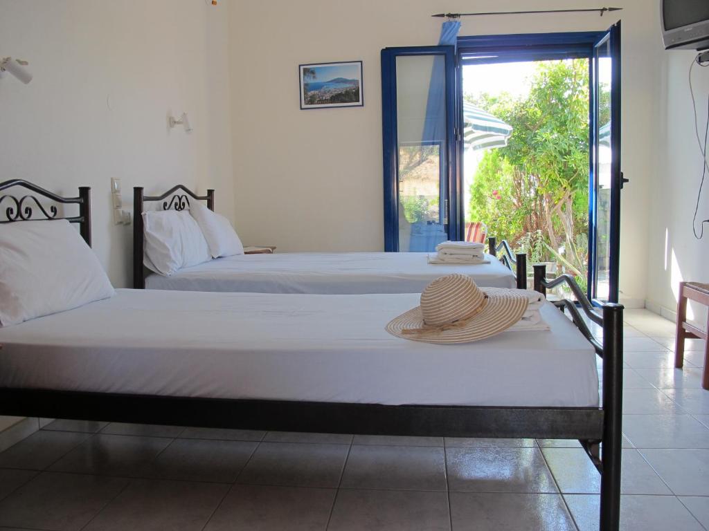 two beds in a room with a hat on a table at Porto Kastri Studios in Kastrí