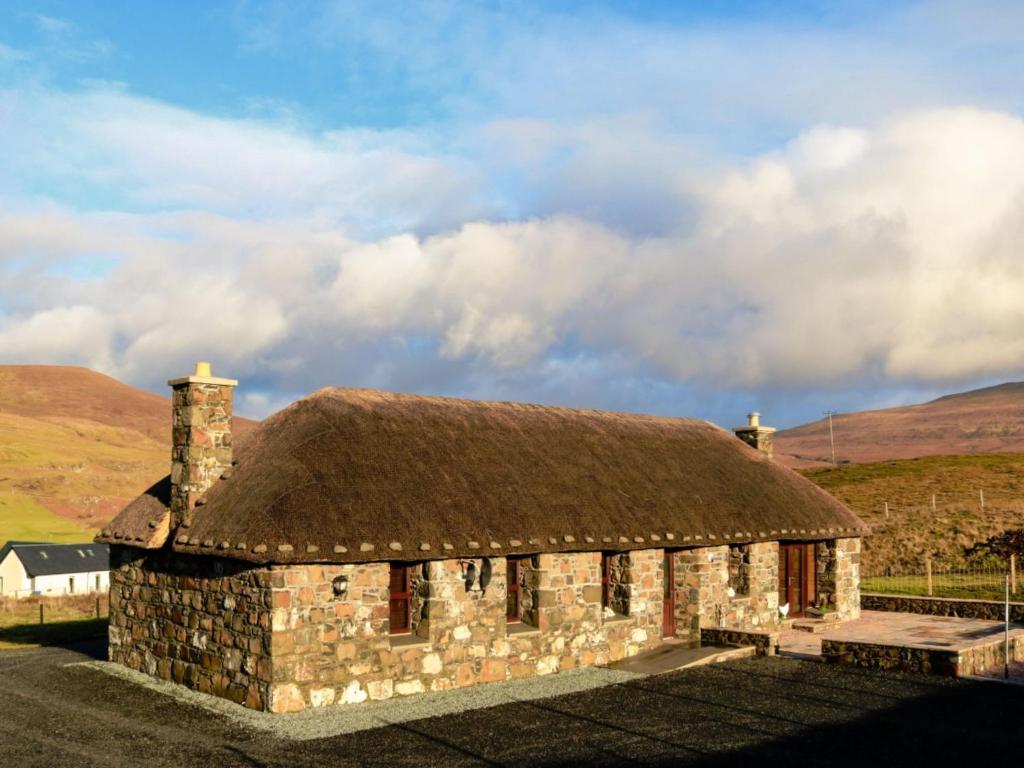 an old stone building with a thatch roof at Holiday Home Glenn Cottage by Interhome in Uig