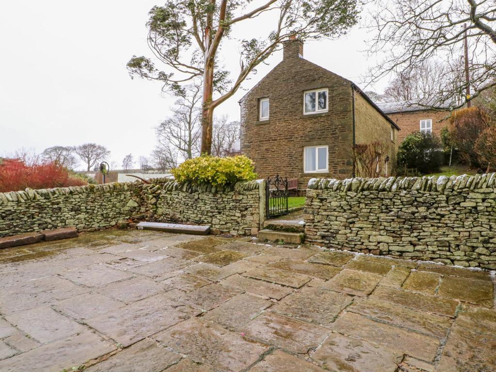 a stone wall and a house behind a stone fence at Bowden Head Farmhouse Cottage in Highpeak Junction