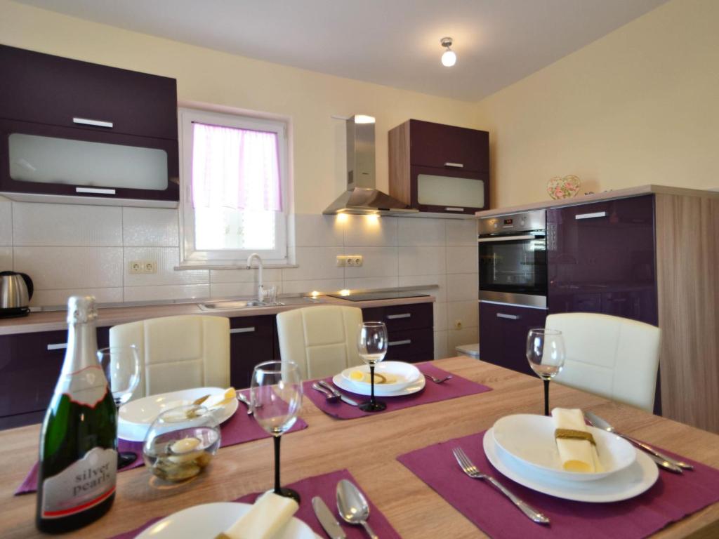 een keuken met een houten tafel en een fles wijn bij Apartment Dević by Interhome in Sukošan