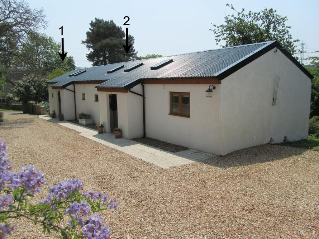 un pequeño edificio blanco con paneles solares en 2 Shippen Cottages en Cotleigh