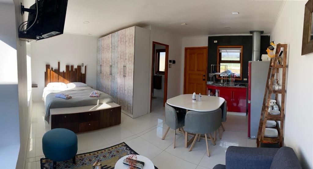 a bedroom with a bed and a table and a kitchen at Departamentos KM 5 in Coihaique