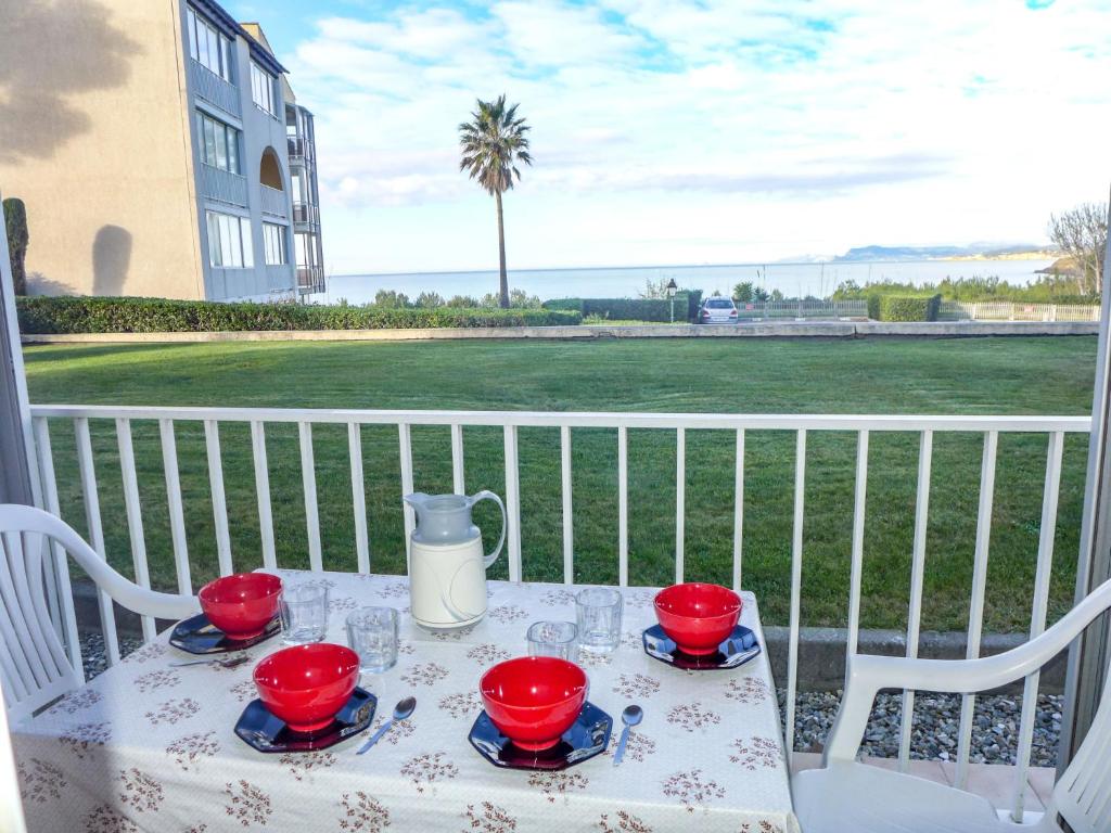 une table avec des bols rouges et des verres sur un balcon dans l'établissement Apartment Le Grand Large by Interhome, à Six-Fours-les-Plages