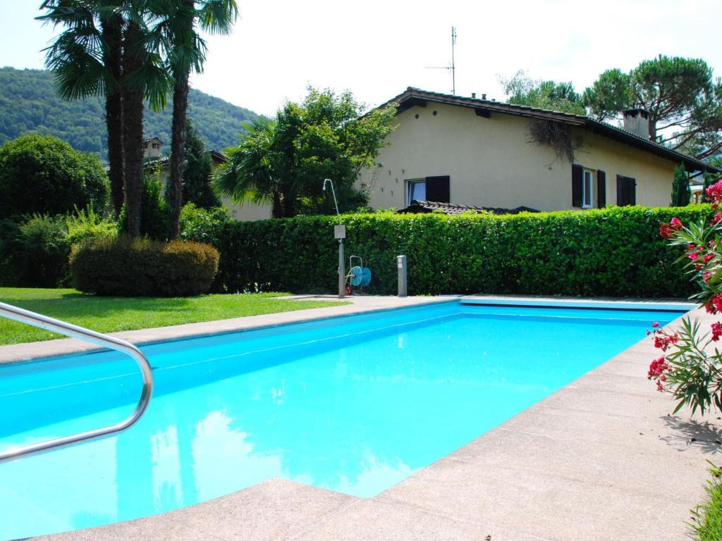 a blue swimming pool in front of a house at Apartment Caslago-1 by Interhome in Caslano
