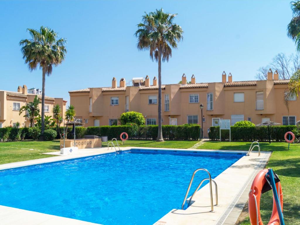 una piscina frente a un edificio con palmeras en Holiday Home Reserva de Alvarito, en Marbella