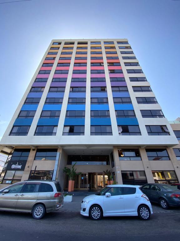 two cars parked in a parking lot in front of a building at Gran Cavancha Suite in Iquique