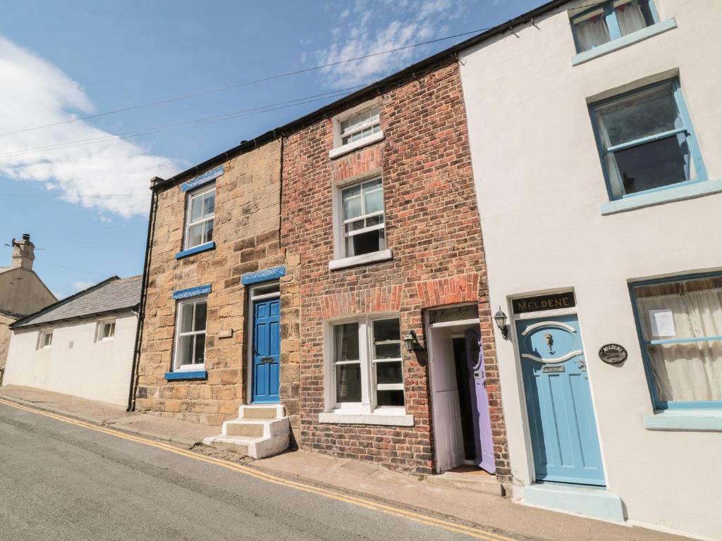 a brick house with a blue door on a street at Clevelyn in Staithes