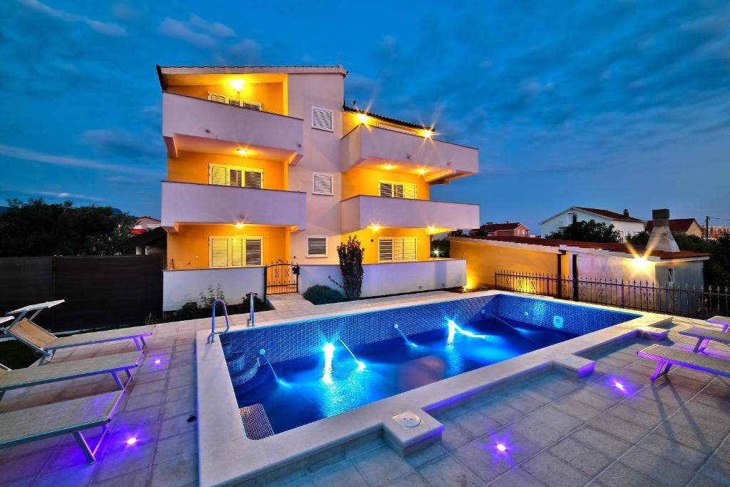 uma villa com piscina em frente a uma casa em Villa Apartments Olivetum em Kaštela