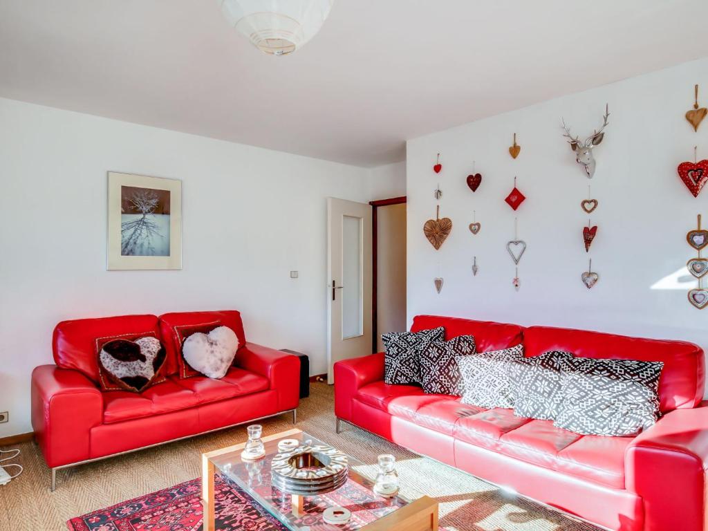 Apartment Fleurs des Alpes-1 by Interhome في سان جيرفيه ليه بان: غرفة معيشة بها كنبتين حمراء وطاولة
