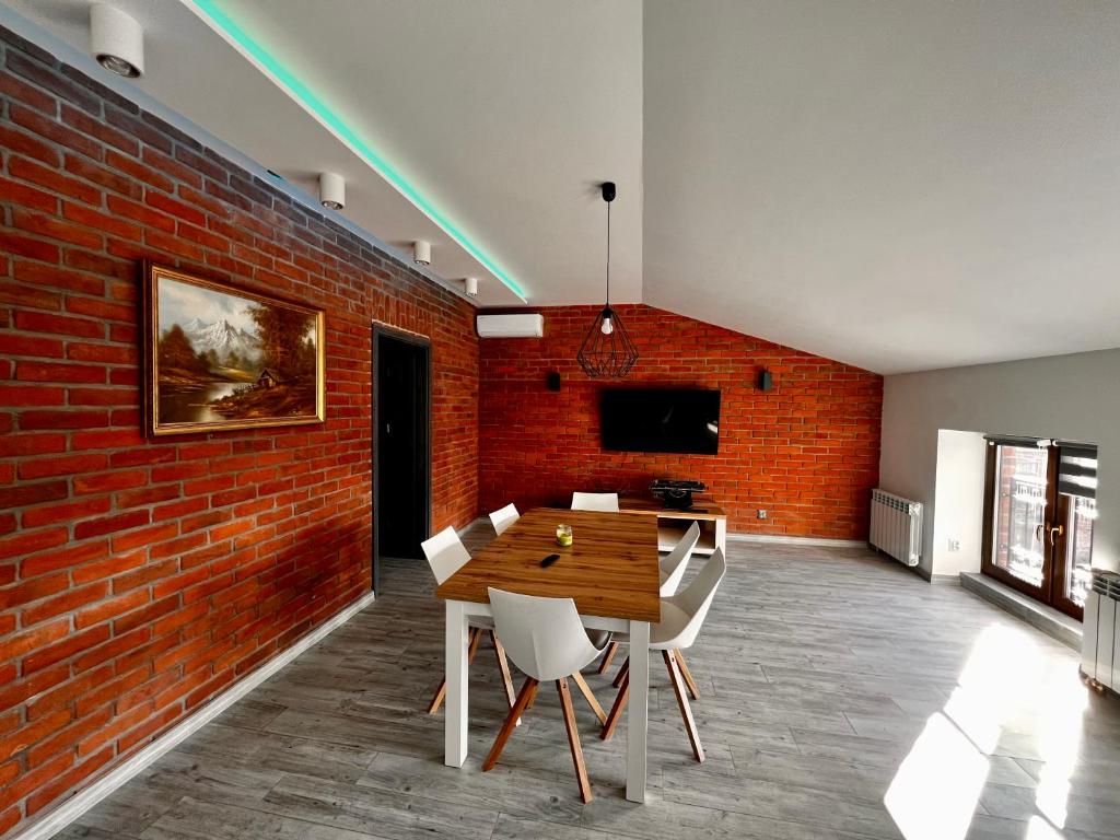 jadalnia z ceglaną ścianą oraz stołem i krzesłami w obiekcie Apartament na 1 Maja -4- w mieście Skierniewice