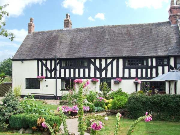 a black and white house with a garden and flowers at Stallington Hall Farm in Fulford