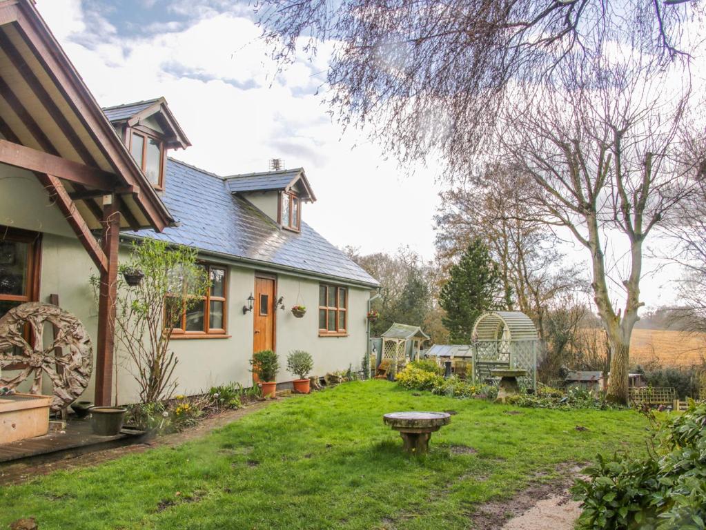 a white house with a yard with a bench at Gardeners Cottage in Nantwich