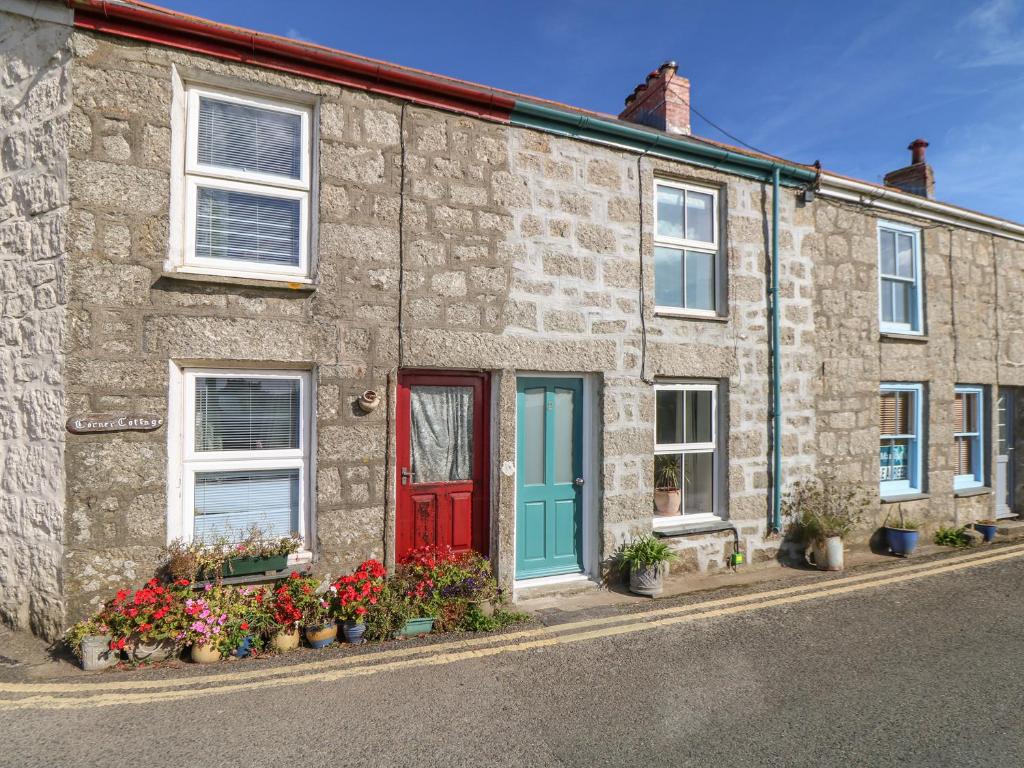 a stone house with a red door and flowers at Westerly Cottage in Penzance