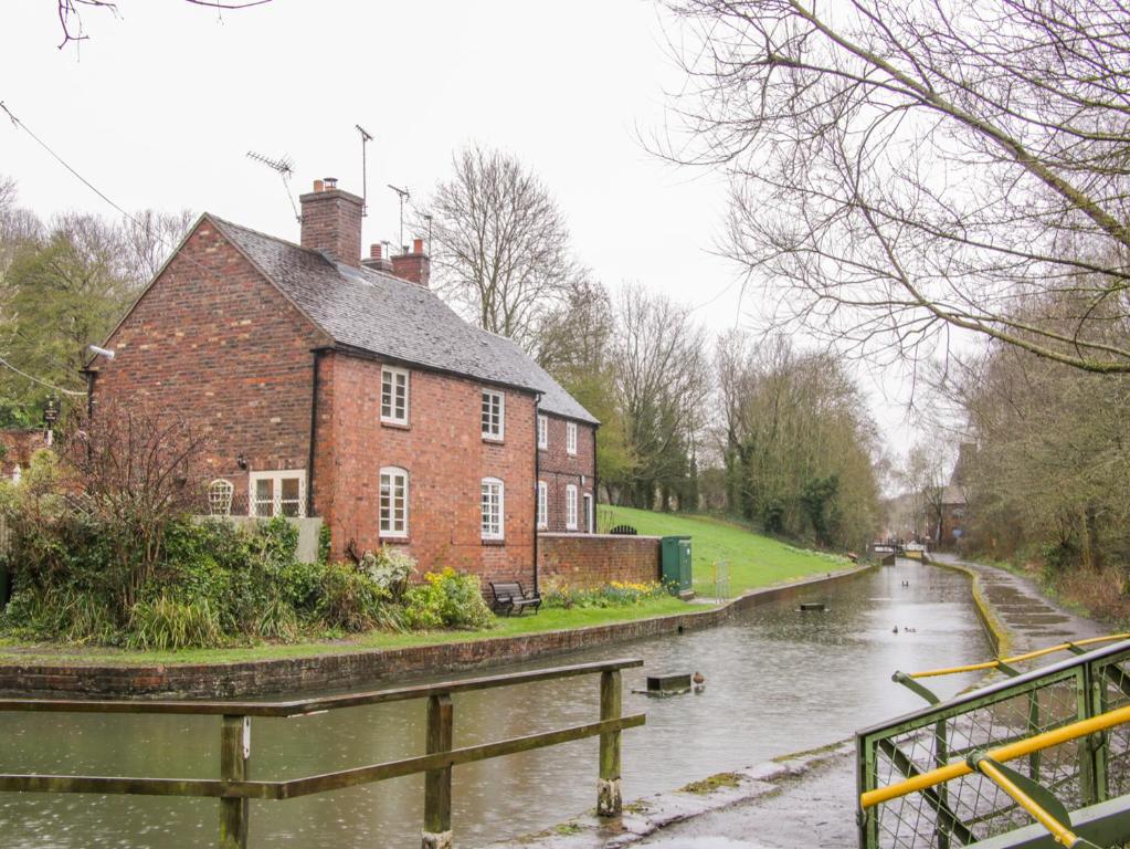 a brick building next to a river with a house at Tub Boat Cottage in Telford