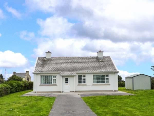 a small white house in a grassy field at Ocean View in Ballinskelligs