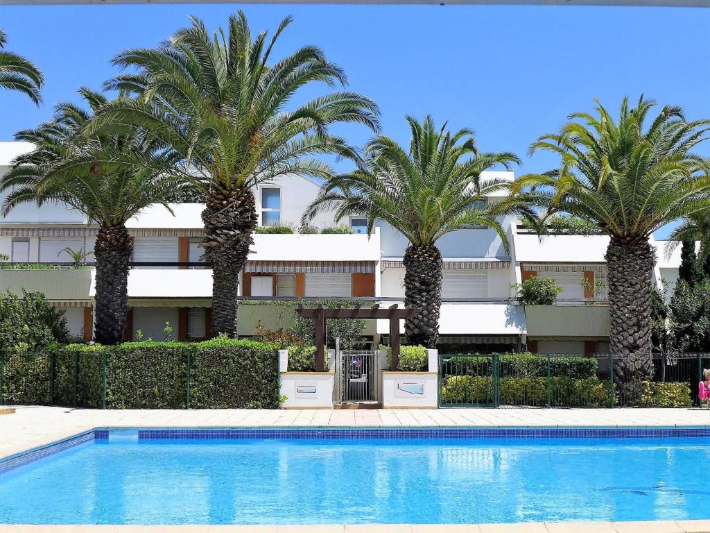 un hôtel avec des palmiers en face d'une piscine dans l'établissement Apartment Les Cyprianes-7 by Interhome, à La Grande Motte