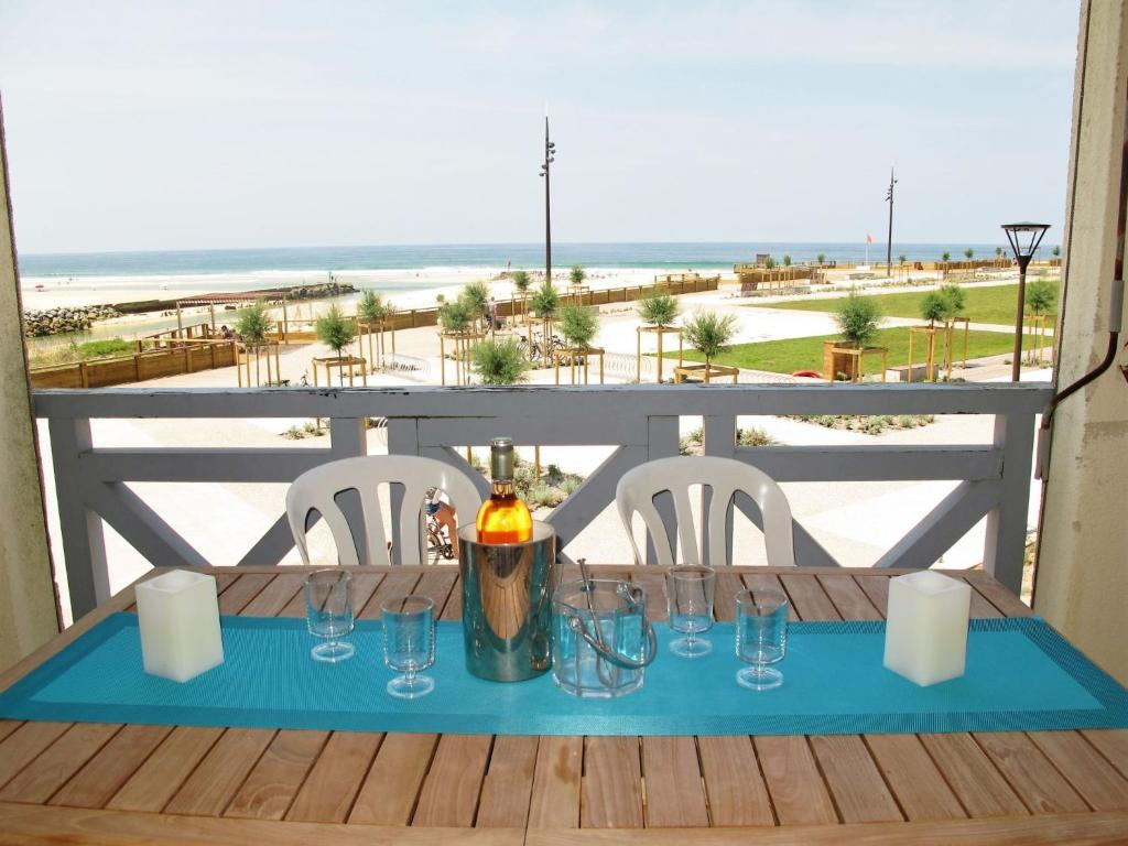 a table with glasses and a candle on a balcony with the beach at Apartment Grand Pavois-4 by Interhome in Mimizan-Plage