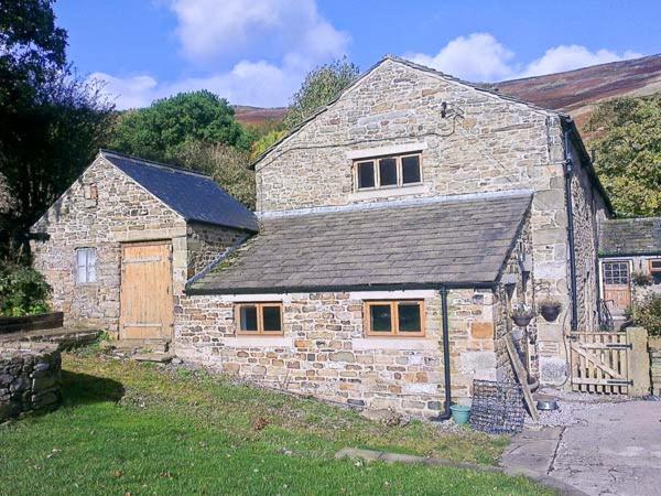 una antigua casa de piedra con puerta de madera en The Stables en Edale