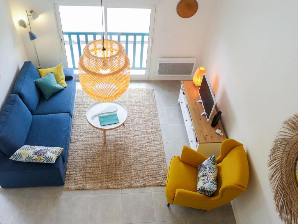 uma sala de estar com um sofá azul e cadeiras amarelas em Apartment Elaura by Interhome em Biarritz