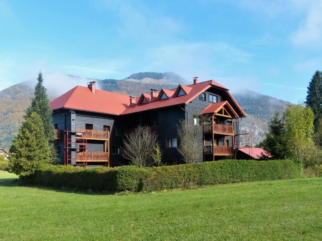 a large house with a red roof on a green field at Apartment Adlerhorst - Top 5 by Interhome in Grünau im Almtal