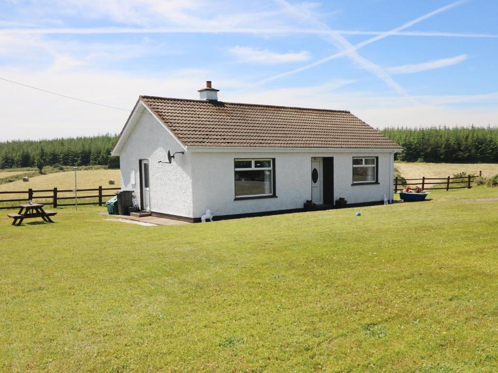 uma pequena casa branca num campo relvado em Clash-Brack em Dungarvan